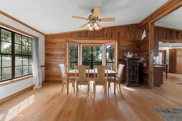 dining space with light hardwood / wood-style floors, wooden walls, and vaulted ceiling