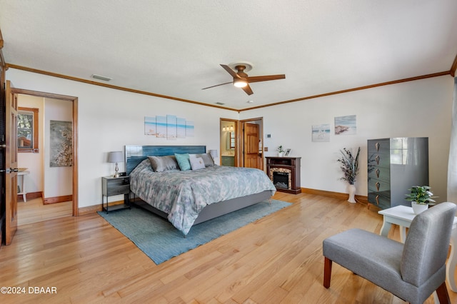 bedroom featuring ceiling fan, light hardwood / wood-style floors, a textured ceiling, and ornamental molding