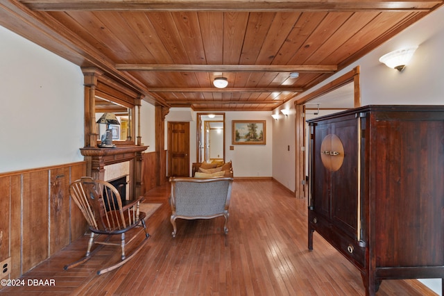 living area featuring ornate columns, beamed ceiling, wood walls, wood-type flooring, and wood ceiling