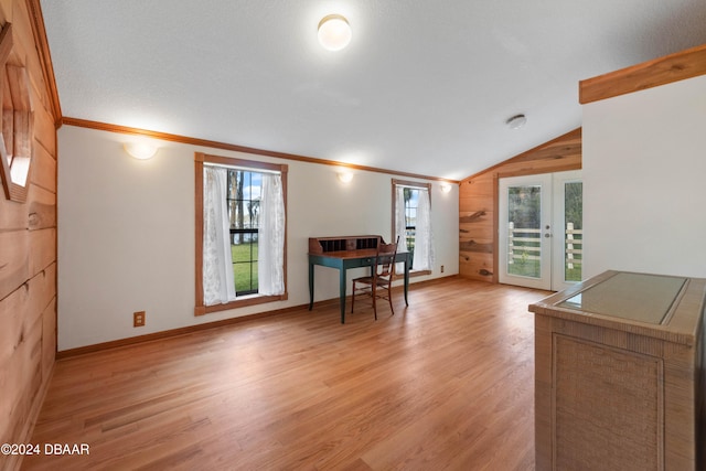 interior space featuring light hardwood / wood-style floors, lofted ceiling, wooden walls, and french doors