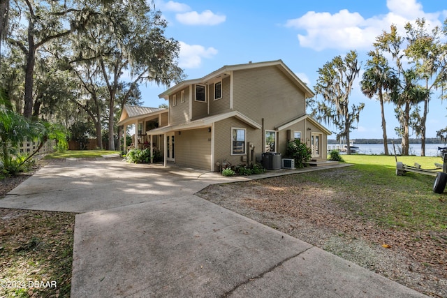 exterior space featuring a water view, a yard, and central AC