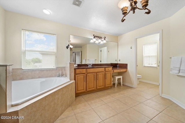 bathroom with toilet, vanity, tile patterned floors, and a relaxing tiled tub