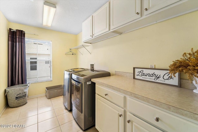 laundry area featuring cabinets, washing machine and clothes dryer, light tile patterned floors, and a textured ceiling