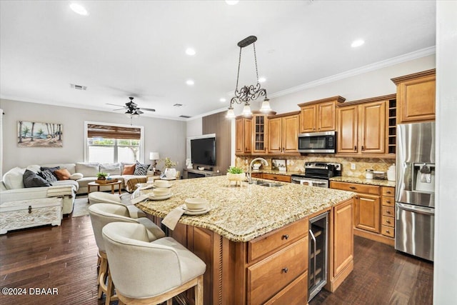 kitchen featuring a kitchen bar, an island with sink, dark hardwood / wood-style floors, appliances with stainless steel finishes, and wine cooler