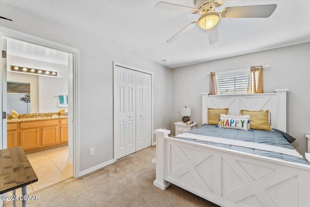 bedroom featuring light carpet, ceiling fan, a textured ceiling, connected bathroom, and a closet