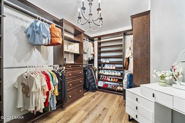 walk in closet with a chandelier and light wood-type flooring