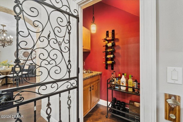 wine cellar with bar area, a notable chandelier, and dark hardwood / wood-style floors