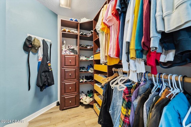 walk in closet with light hardwood / wood-style floors