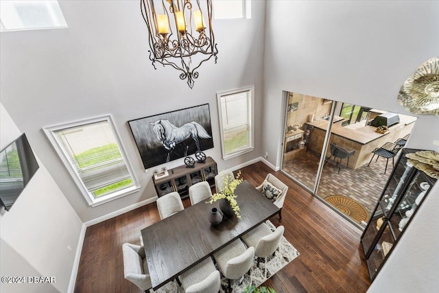 living room with dark hardwood / wood-style flooring, a chandelier, and a towering ceiling