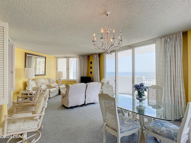 carpeted dining area with a textured ceiling, a water view, and a notable chandelier