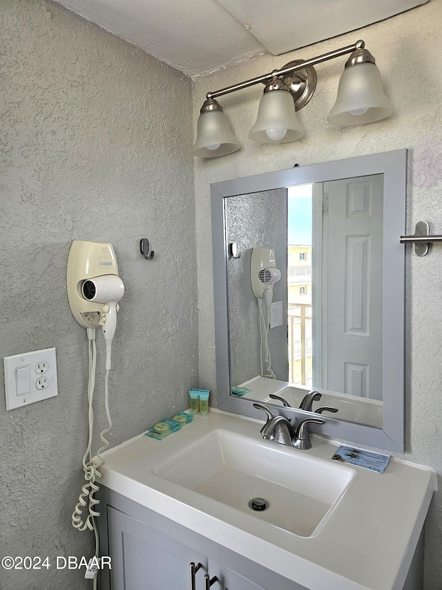 bathroom with a textured wall and vanity