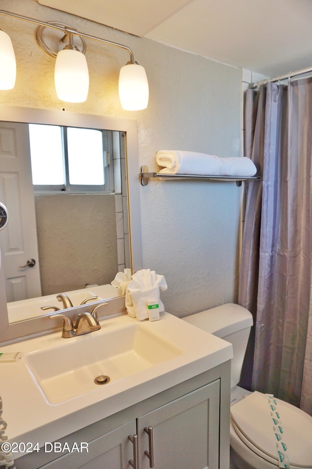 bathroom featuring a textured wall, toilet, vanity, and a shower with curtain