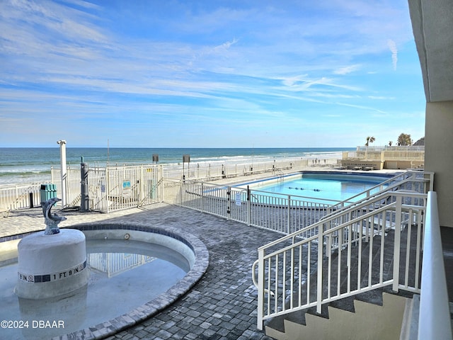 pool featuring fence, a patio area, and a water view