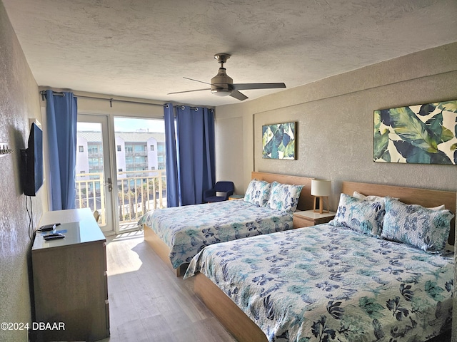 bedroom featuring wood finished floors, a textured ceiling, ceiling fan, a textured wall, and access to exterior