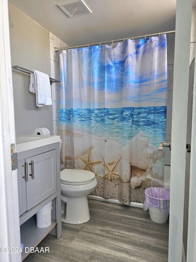bathroom with a shower with curtain, toilet, visible vents, wood finished floors, and vanity