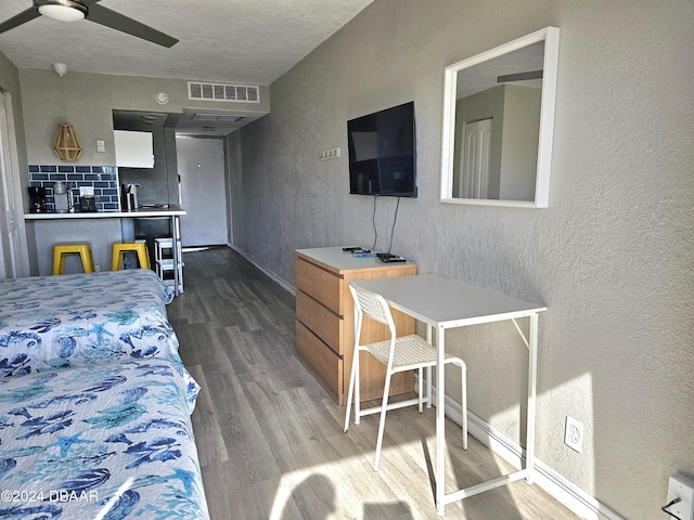 bedroom featuring dark wood finished floors, baseboards, visible vents, a ceiling fan, and a textured wall