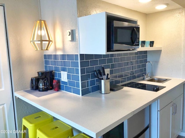 kitchen featuring open shelves, a textured wall, a sink, black electric stovetop, and tasteful backsplash