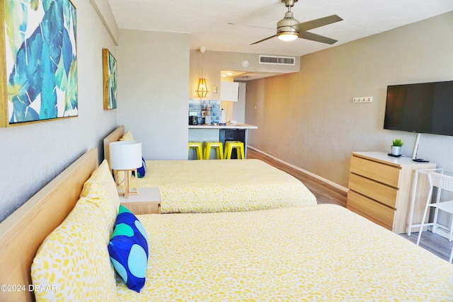 bedroom featuring baseboards, wood finished floors, visible vents, and a ceiling fan