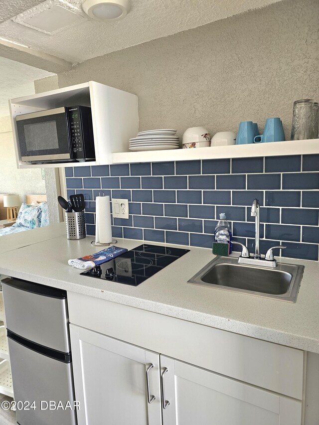 219 S Atlantic Ave Unit 428, Daytona Beach, FL 32118 - kitchen featuring a sink, decorative backsplash, white cabinets, light countertops, and a textured wall