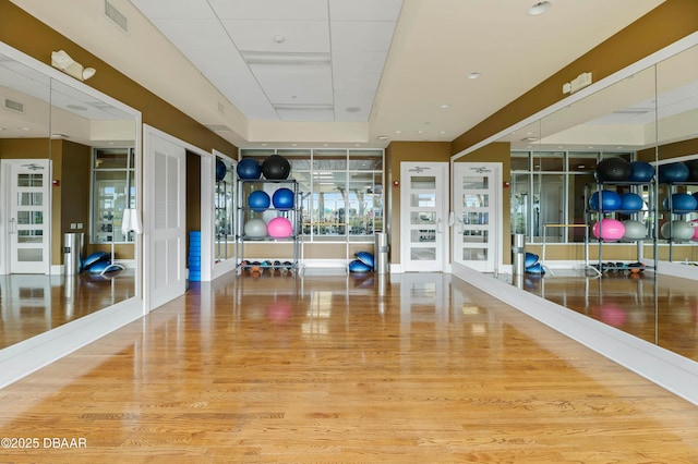 exercise room with visible vents, french doors, and wood finished floors