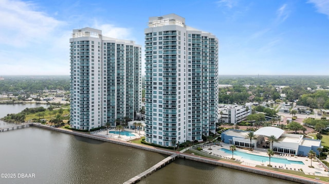 view of building exterior featuring a water view, a view of city, and a community pool