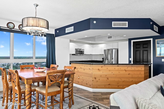 dining room with wood finished floors, a notable chandelier, and visible vents