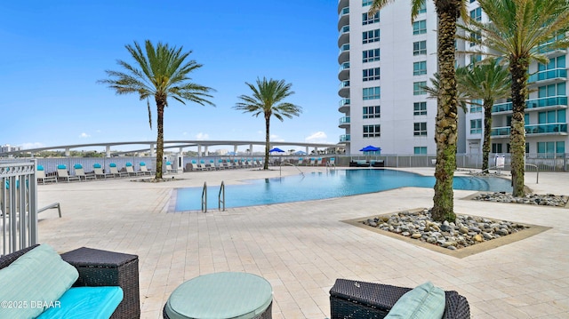 community pool with a patio area and fence