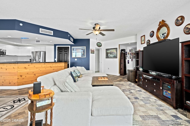 living room featuring a textured ceiling, a ceiling fan, and visible vents