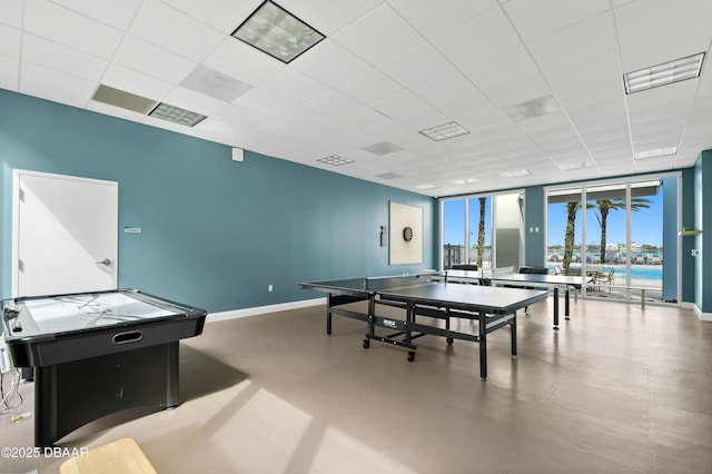 recreation room with a paneled ceiling, concrete floors, floor to ceiling windows, visible vents, and baseboards