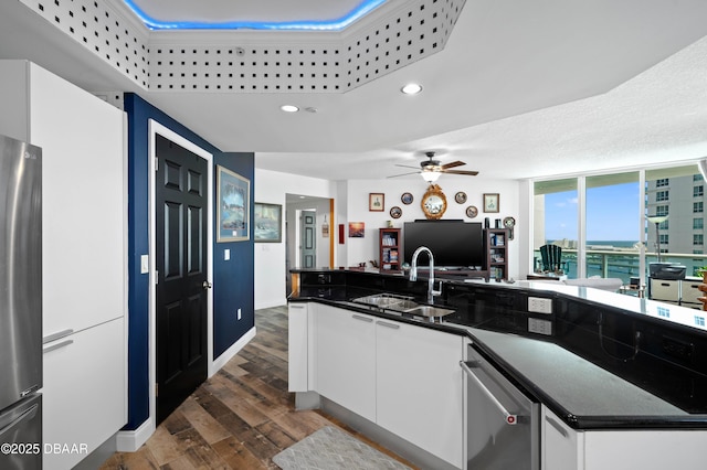 kitchen featuring dark wood-type flooring, white cabinetry, a ceiling fan, a sink, and open floor plan