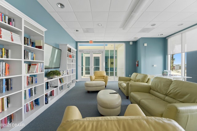 carpeted living room with expansive windows, french doors, and a drop ceiling