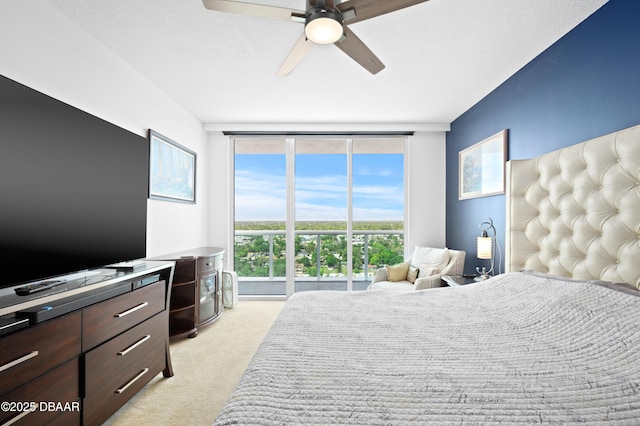 bedroom with ceiling fan, light colored carpet, and a wall of windows