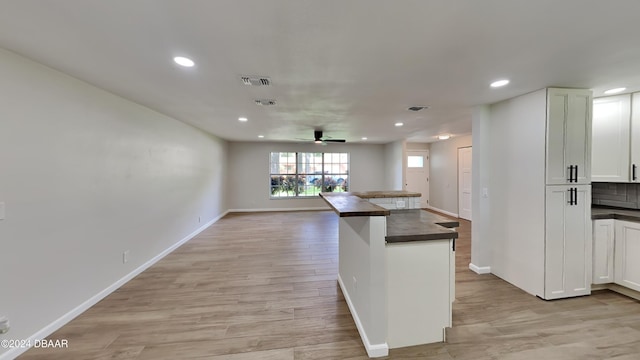 kitchen featuring backsplash, light hardwood / wood-style flooring, white cabinetry, and ceiling fan