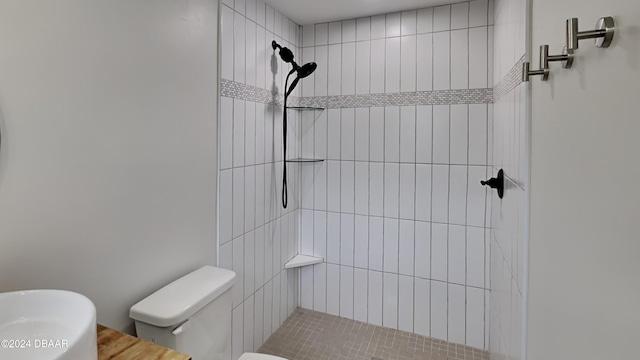 bathroom featuring tiled shower, hardwood / wood-style floors, and toilet