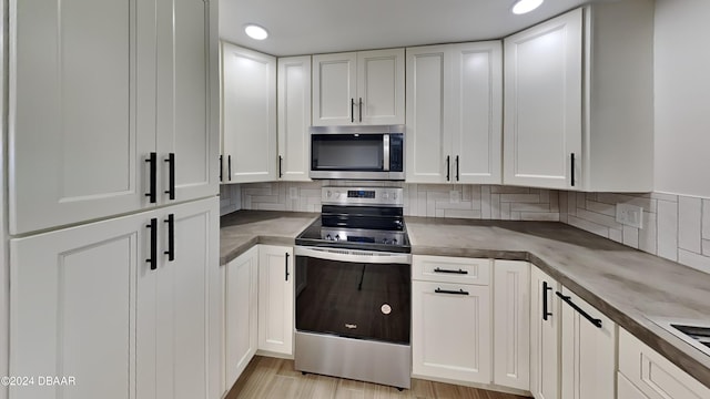 kitchen featuring tasteful backsplash, white cabinetry, stainless steel appliances, and light wood-type flooring