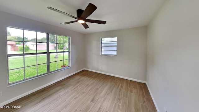 empty room with a wealth of natural light, ceiling fan, and light hardwood / wood-style flooring