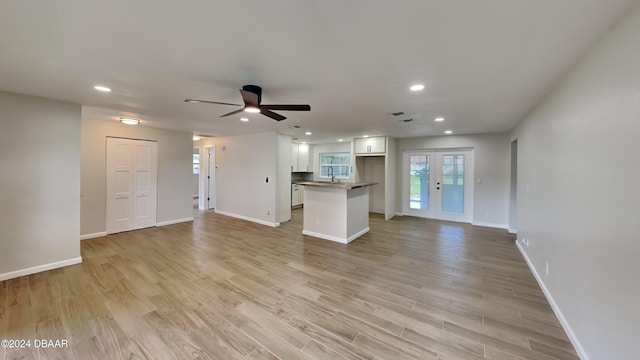 unfurnished living room with ceiling fan, sink, and light hardwood / wood-style flooring