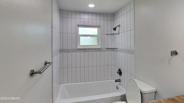 bathroom with toilet and tiled shower / bath