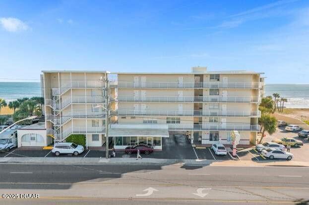 view of building exterior featuring a water view and uncovered parking