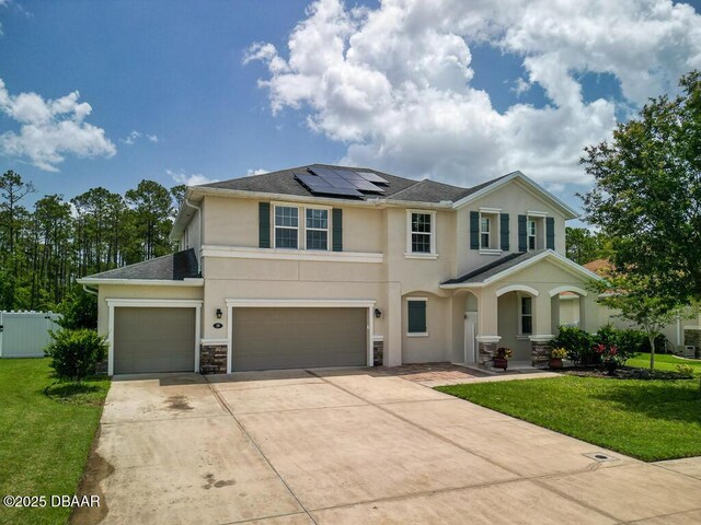 19 Abacus Ave, Ormond Beach, FL 32174 - view of front of house with roof mounted solar panels, stucco siding, driveway, stone siding, and a shingled roof