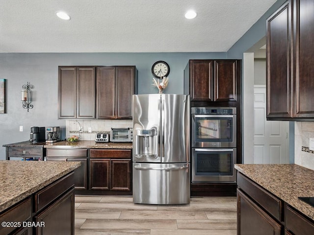 19 Abacus Ave, Ormond Beach, FL 32174 - kitchen featuring stainless steel appliances, dark brown cabinets, tasteful backsplash, a textured ceiling, and light wood finished floors