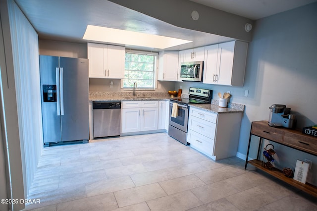 2 Springwood Sq, Port Orange, FL 32129 - kitchen featuring stainless steel appliances, a sink, light stone countertops, white cabinets, and baseboards