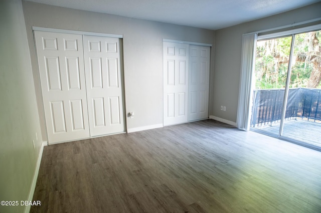 2 Springwood Sq, Port Orange, FL 32129 - unfurnished bedroom with access to exterior, wood finished floors, baseboards, and two closets