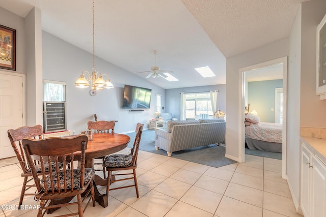 dining room featuring vaulted ceiling with skylight, ceiling fan with notable chandelier, a textured ceiling, and light tile patterned flooring