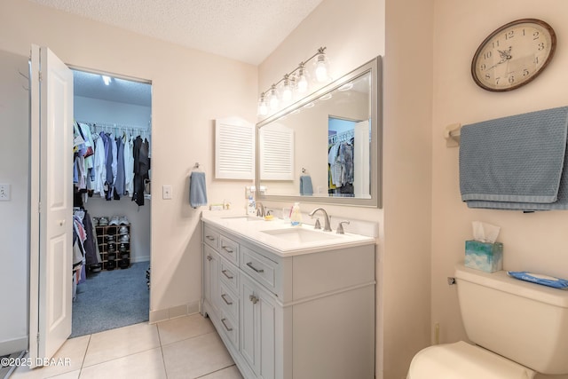 bathroom featuring toilet, double vanity, a textured ceiling, and a sink