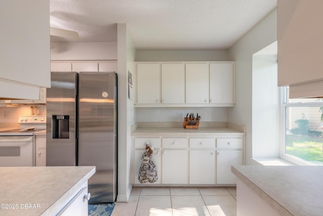 kitchen featuring light countertops, white cabinets, stainless steel fridge, and white range with electric cooktop