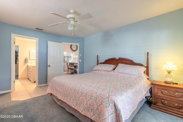 carpeted bedroom with visible vents, connected bathroom, ceiling fan, a textured ceiling, and tile patterned flooring