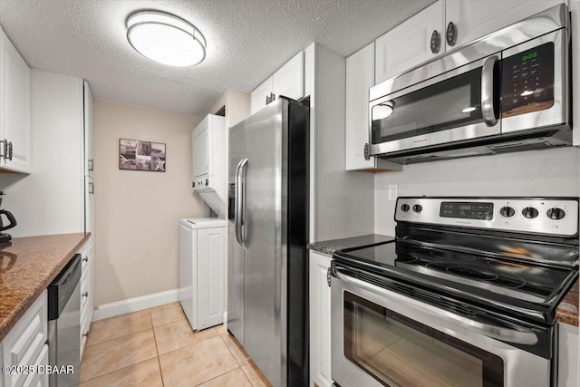 4505 S Atlantic Ave Unit 605, Ponce Inlet, FL 32127 - kitchen featuring appliances with stainless steel finishes, stacked washer / dryer, white cabinets, a textured ceiling, and light tile patterned floors