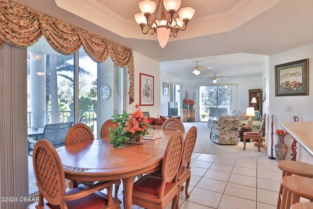 dining area featuring ceiling fan with notable chandelier, a raised ceiling, light tile patterned floors, and crown molding