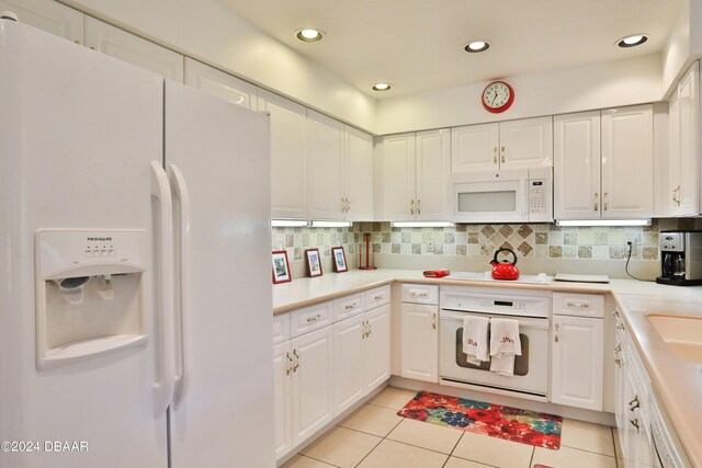 kitchen with white appliances, decorative backsplash, light tile patterned floors, and white cabinets